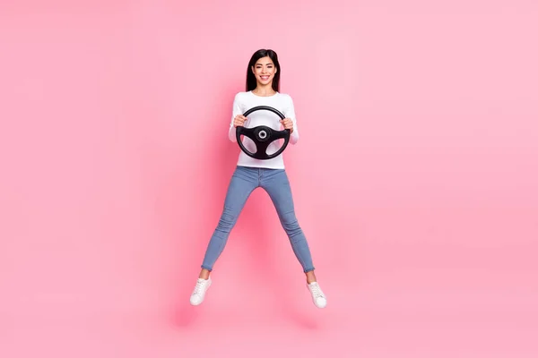 Full size photo of cool millennial brunette lady jump drive wear shirt jeans footwear isolated on pink background — Foto Stock