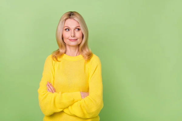 Photo of interested curious aged lady cross arms look empty space wear yellow sweater isolated green color background — Foto de Stock