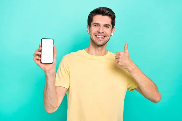 Photo of funny brunet young guy show telephone thumb up wear t-shirt headphones isolated on teal color background — Fotografia de Stock