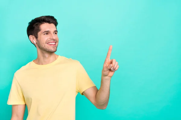 Photo of optimistic brunet millennial guy index promo wear t-shirt headphones isolated on teal color background — стоковое фото