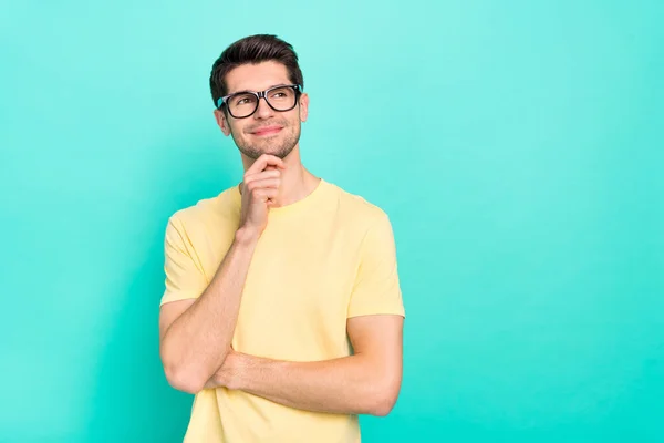 Photo of smart brunet young guy look empty space wear eyewear yellow t-shirt isolated on turquoise color background — Zdjęcie stockowe
