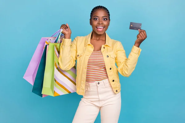 Portrait of attractive cheerful girl holding bags clothes bank card order use delivery isolated over bright blue color background — Stok fotoğraf