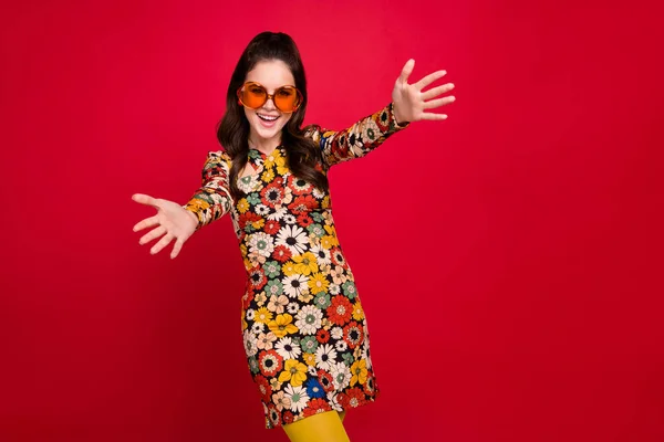 Photo of shiny excited woman wear flower print dress hear eyewear open arms empty space isolated red color background – stockfoto