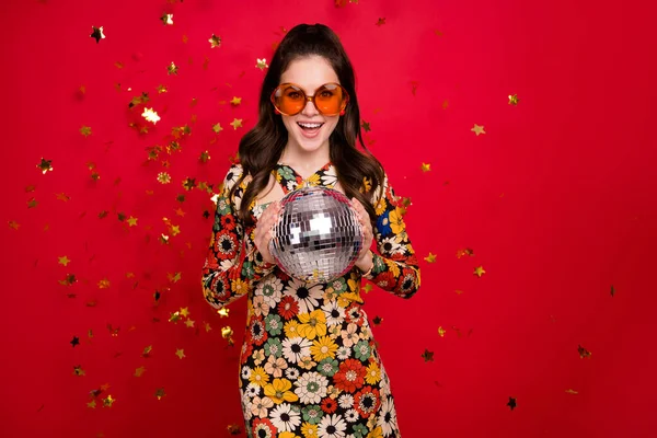 Portret van aantrekkelijke vrolijke girly meisje holding zilver disco bal plezier geïsoleerd over helder rood kleur achtergrond — Stockfoto