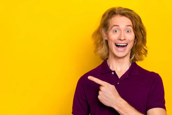 Photo of impressed millennial ginger guy indicate promo wear purple polo isolated on yellow color background — Zdjęcie stockowe