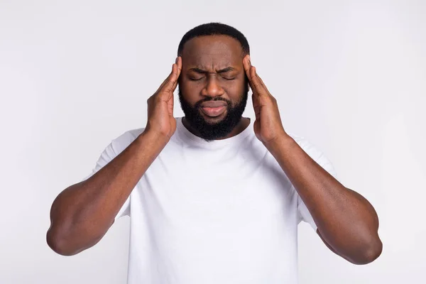 Photo of unhappy tired guy dressed casual t-shirt arms temples having pain isolated white color background — Stock Fotó