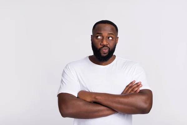 Photo of attractive doubtful guy dressed casual t-shirt arms crossed looking empty space isolated white color background — Stockfoto