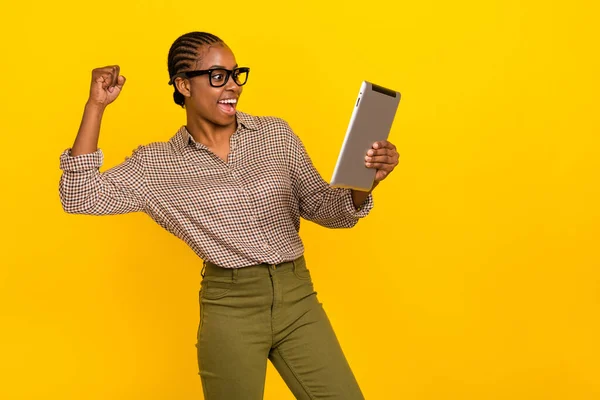 Photo of funny lucky lady dressed checkered shirt spectacles chatting modern device rising fist isolated yellow color background — Photo