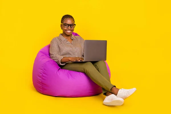 Foto von süßen hübschen Dame kariert Hemd sitzend Bean Bag arbeiten moderne Gadget isoliert gelbe Farbe Hintergrund — Stockfoto