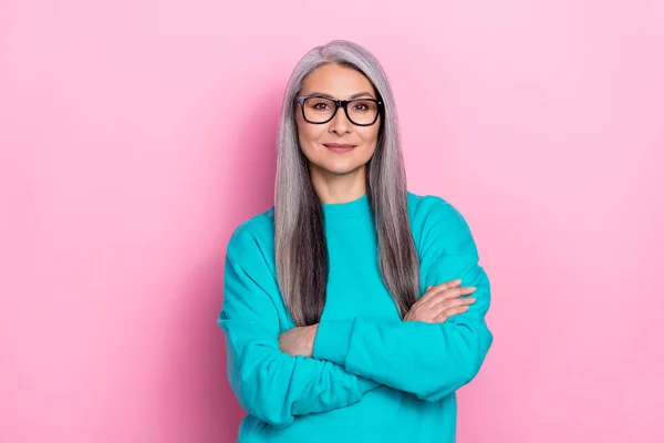 Fénykép bájos pozitív nyugdíjas nő kék pulóver szemüveg karok keresztbe elszigetelt rózsaszín háttér — Stock Fotó