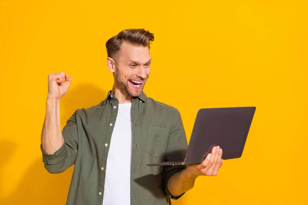 Портрет привабливого щасливого веселого хлопця хакера з використанням ноутбука радісного бронювання ізольовано на яскраво-жовтому кольоровому фоні — стокове фото