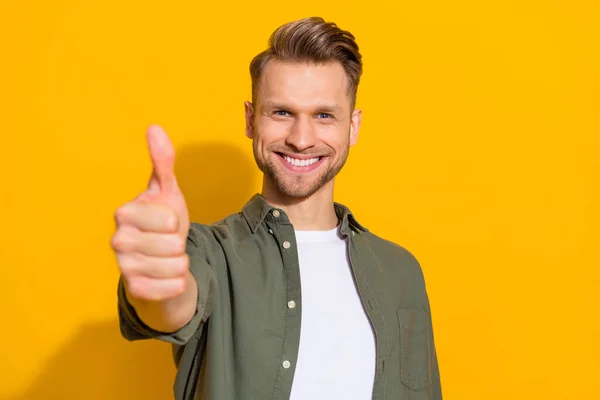 Portrait of attractive cheerful content guy giving thmbup ad advert isolated over bright yellow color background — стоковое фото