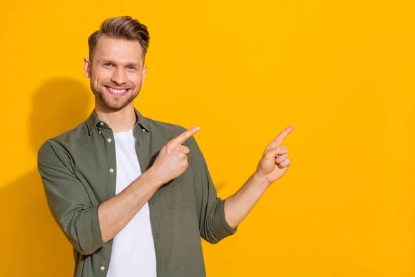 Porträtt av attraktiv glad blond kille visar kopia tomt utrymme annons isolerad över ljusa gula färg bakgrund — Stockfoto