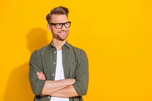 Portrait of attractive cheerful content guy folded arms thinking copy empty space isolated over bright yellow color background — стоковое фото