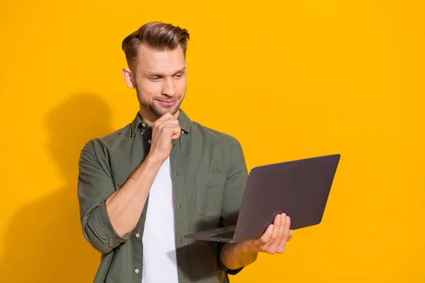 Portrait of attractive minded smart guy using laptop deciding order eshop booking isolated over bright yellow color background — стоковое фото