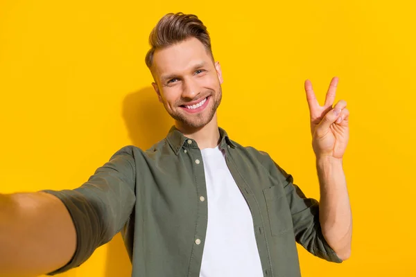 Self-portrait of attractive cheerful guy showing v-sign rest good mood isolated over bright yellow color background — Stok fotoğraf