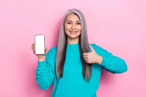 Портрет позитивной дружелюбной дамы показывают большой палец вверх пустой дисплей космический телефон изолирован на розовом фоне цвета — стоковое фото