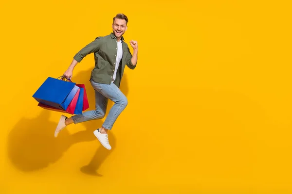 Full längd kroppsstorlek bild av attraktiv lycklig kille hoppa bär saker kör kopia utrymme isolerad över ljusgul färg bakgrund — Stockfoto