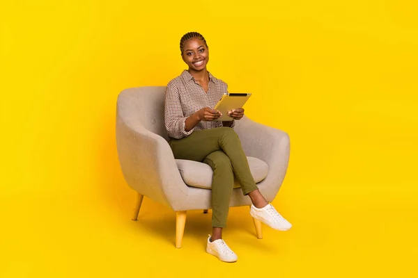 Foto van grappige schattige dame gekleed geruite shirt zit stoel typen moderne gadget geïsoleerde gele kleur achtergrond — Stockfoto
