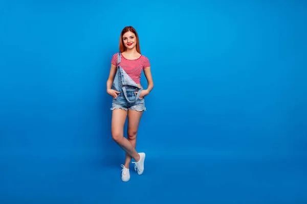 Full length photo of adorable charming woman wear jeans outfit walking hands arms pockets empty space isolated blue color background — Stockfoto