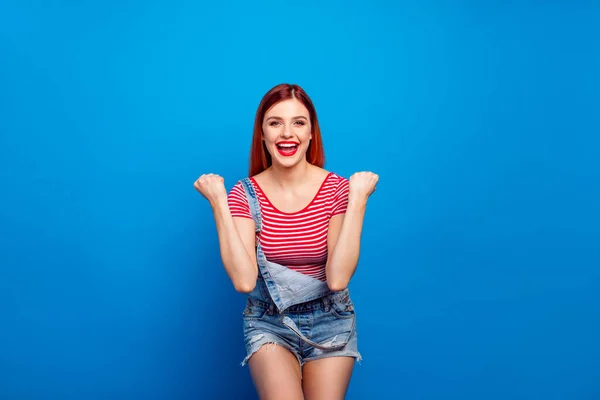 Photo of excited lucky young lady dressed denim clothes screaming rising fists isolated blue color background — ストック写真