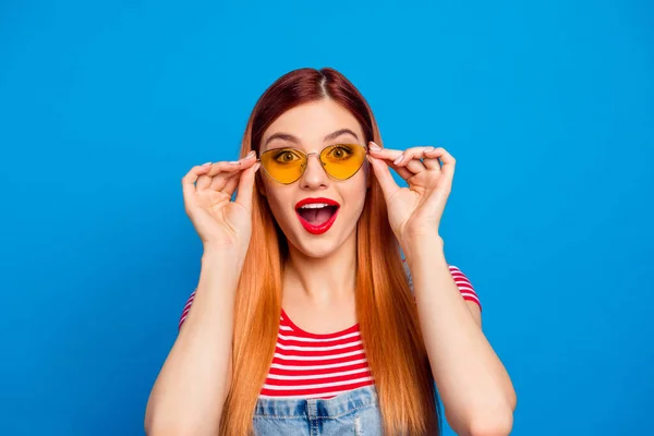 Photo of impressed funky young lady dressed denim clothes arms dark eyewear isolated blue color background — 스톡 사진