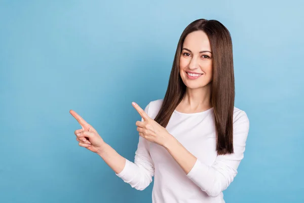 Photo of optimistic mature brunette lady index promo wear white pullover isolated on blue color background — Zdjęcie stockowe