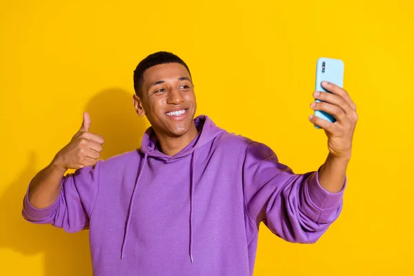 Portrait of handsome trendy cheerful guy taking making selfie showing thumbup isolated over bright yellow color background — Stockfoto