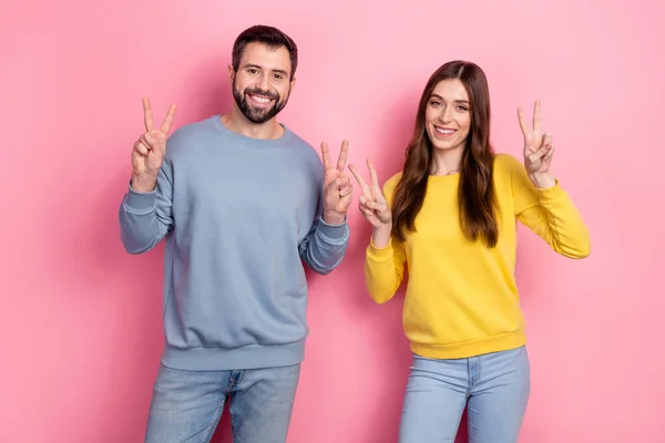 Portrait of attractive cheerful couple showing double v-sign good mood party isolated over pink pastel color background — Foto Stock