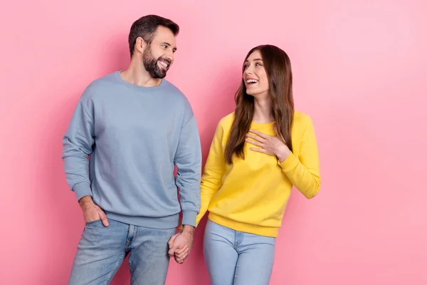 Portrait of attractive cheerful couple holding hands laughing good mood isolated over pink pastel color background — Foto de Stock