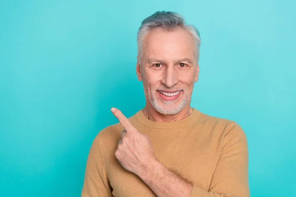 Photo of positive cheerful person indicate finger empty space promo isolated on teal color background — ストック写真