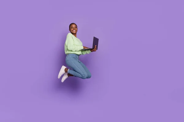 Imagen de cuerpo completo de la joven alegre navegando portátil charlando con amigos aislados en el fondo de color violeta —  Fotos de Stock