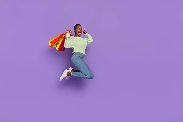 Full body photo of overjoyed crazy female jumping up in excitement go shopping win discount coupon isolated on violet color background — Stock fotografie