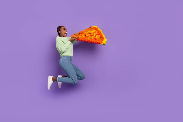Full length picture of excited girl in trendy clothes bite huge pizza slice feeling hungry isolated on purple color background — Fotografia de Stock