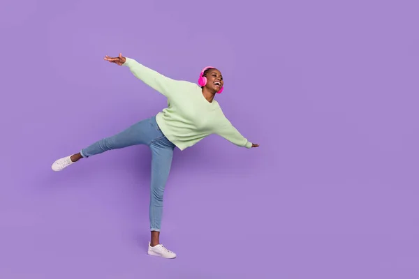 Full length image of young dreamy female crazy dancing in headset fooling around isolated on purple color background — Stockfoto