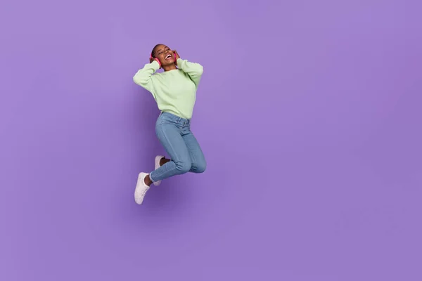 Foto de tamaño completo de la feliz emoción femenina disfrutando de su banda de rock favorita en auriculares aislados sobre fondo de color púrpura —  Fotos de Stock