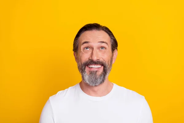 Photo of impressed brunet man look up wear white shirt isolated on yellow color background — Photo