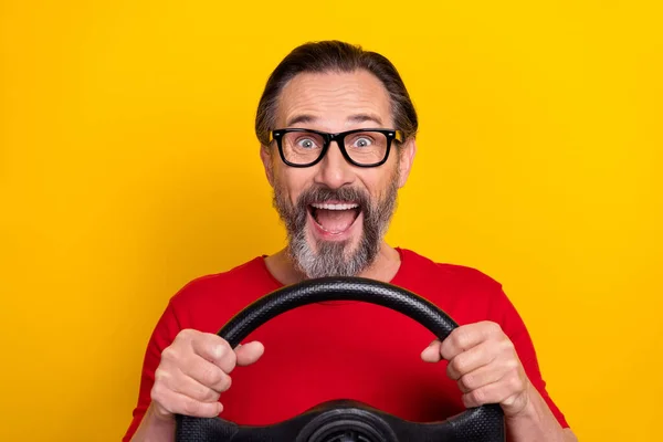 Photo funky excité gars pensionné habillé rouge t-shirt lunettes auto rider bouche ouverte isolé couleur jaune fond — Photo