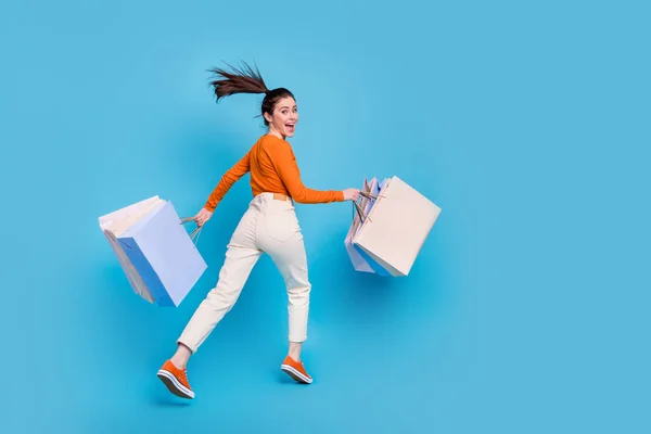 Baksidan bild bakom foto av glada sorglösa flicka kör för att köpa kläder shopping säsong isolerad på blå färg bakgrund — Stockfoto
