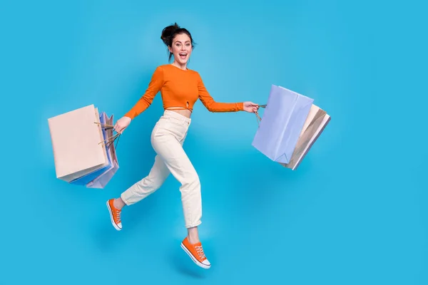 Full size profile side photo of excited girl go shopping buy many fashionable clothes isolated on blue color background — Zdjęcie stockowe