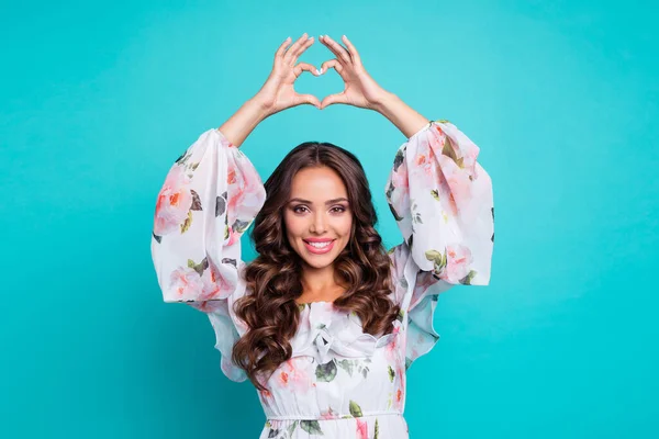 Photo of cheerful good mood woman wear flower print dress rising arms showing heart isolated aquamarine color background — Fotografia de Stock