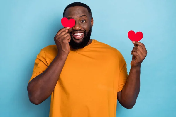 Portrait of attractive cheerful guy holding two hearts closing eye having fun romance isolated over bright blue color background — Photo