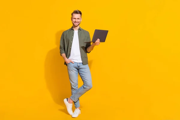 Full length body size view of attractive cheerful guy using laptop booking order isolated over bright yellow color background — Fotografia de Stock