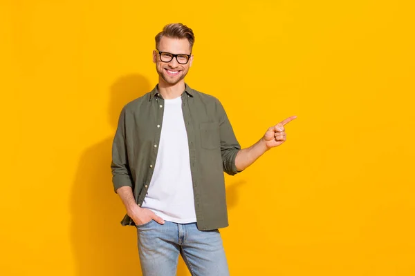 Portrait of attractive cheerful lucky guy showing copy empty blank space ad isolated over bright yellow color background — Stockfoto