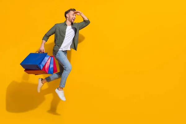 Full length body size view of attractive guy jumping carrying things running look isolated over bright yellow color background — ストック写真