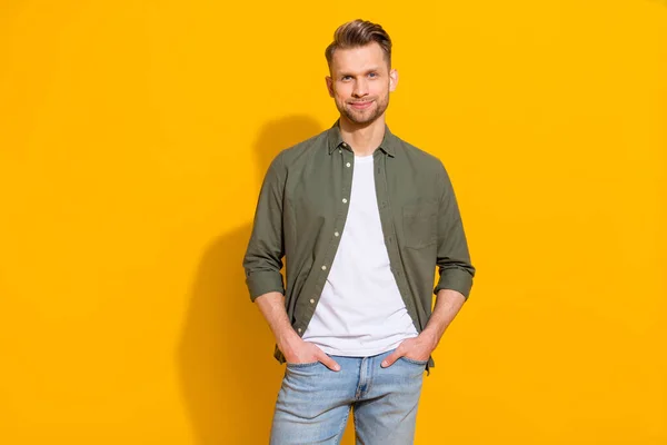 Portrait of attractive cheery content guy holding hands in pockets isolated over vibrant yellow color background — ストック写真