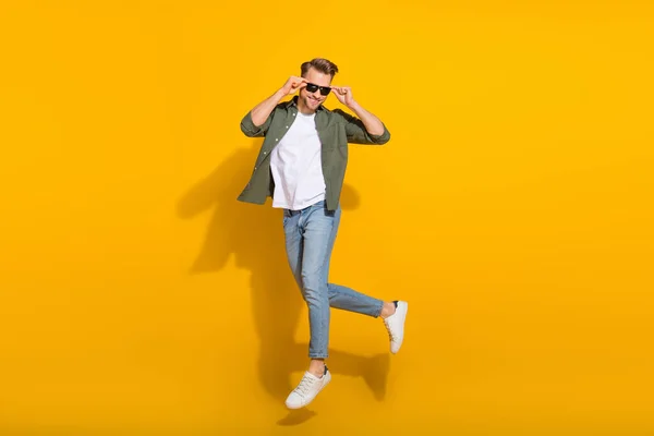 Full length body size view of attractive cheerful guy jumping touching specs stroll isolated over bright yellow color background — Stockfoto