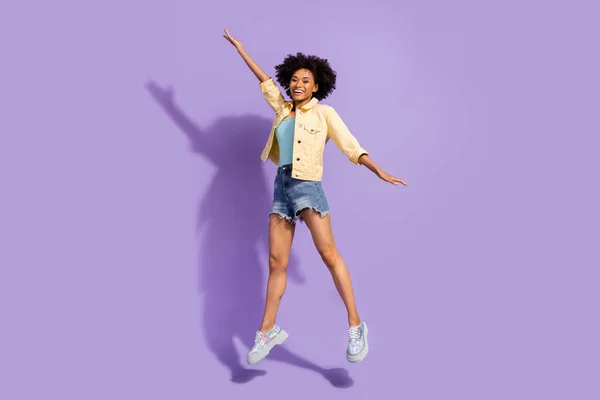 Photo of cute adorable lady wear yellow denim jacket jumping high smiling isolated violet color background — Fotografia de Stock