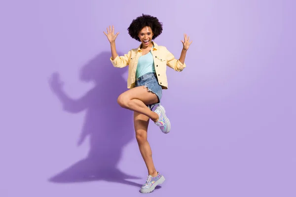 Photo of funny impressed woman dressed yellow jeans rising arms dancing isolated purple color background — ストック写真