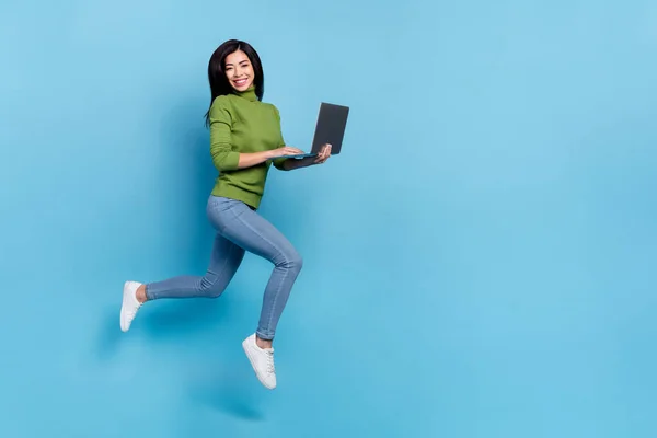 全长图片可爱的年轻的黑发女士跑与笔记本电脑穿跳跃牛仔裤鞋袜隔离蓝色背景 — 图库照片